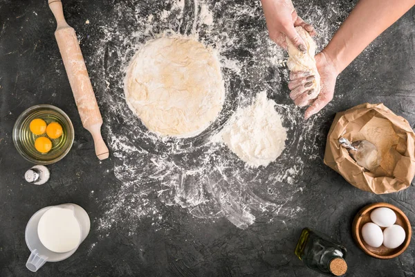 Partial view of woman preparing dough on grey background with flour and ingredients — Stock Photo