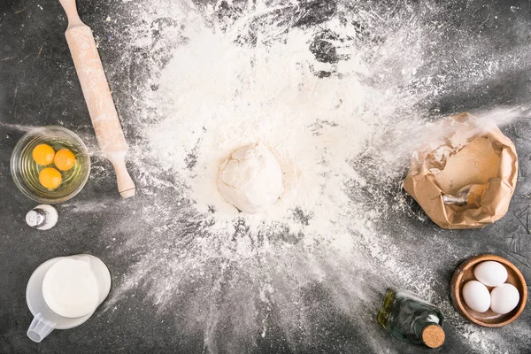 Top view of dough, flour and rolling pin on grey background — Stock Photo