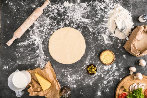 Top view of pizza dough with ingredients on grey background — Stock Photo
