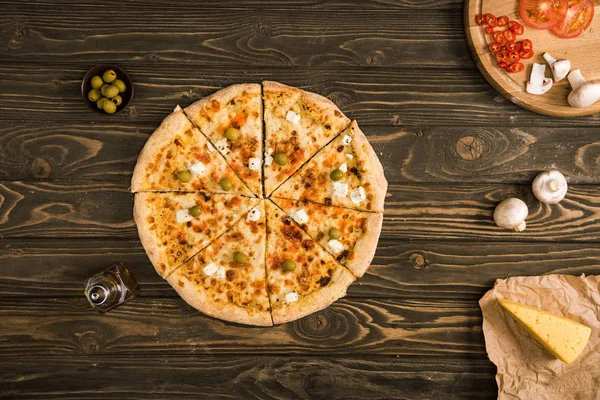 Top view of tasty cheese pizza with ingredients on wooden table — Stock Photo