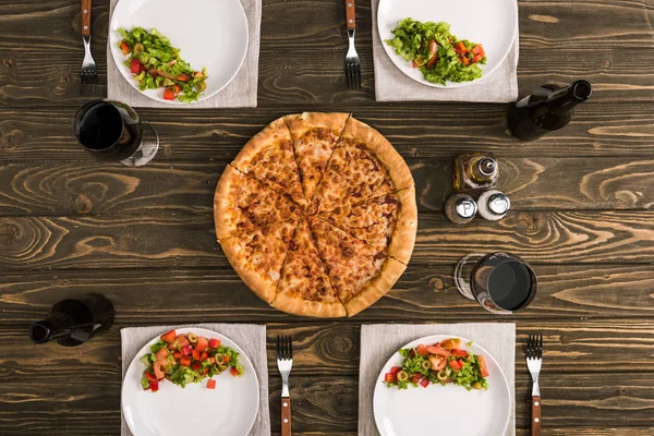 Сервировка стола с пиццей и бокалами вина на деревянном столе — стоковое фото