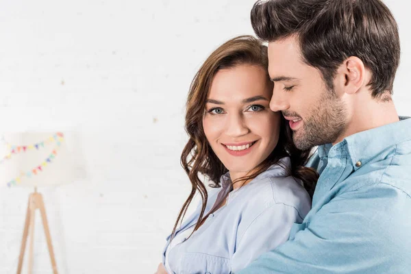 Portrait of man embracing smiling woman at home — Stock Photo