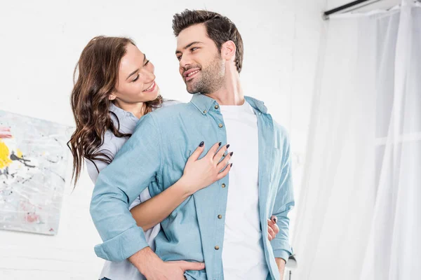 Woman hugging handsome man from behind at home — Stock Photo