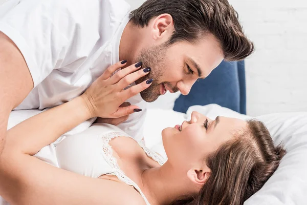 Casal feliz abraçando e olhando um para o outro na cama — Fotografia de Stock