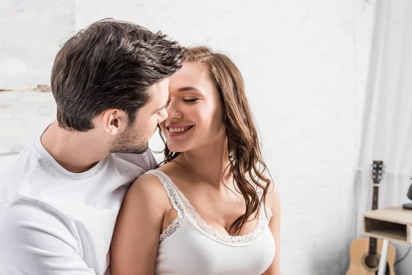 Pareja tiernamente abrazándose y mirándose en la cama - foto de stock