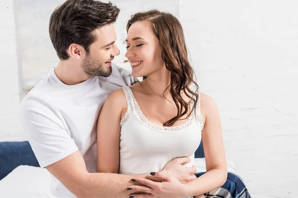 Belo casal abraçando e olhando um para o outro na cama — Fotografia de Stock