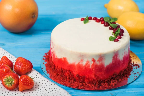 Close up of white cake decorated with red currants and mint leaves near orange and lemons — Stock Photo