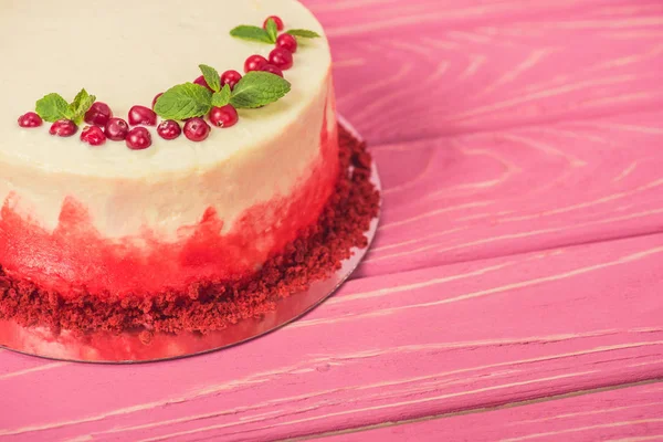 Close up of white cake decorated with currants and mint leaves on pink surface — Stock Photo