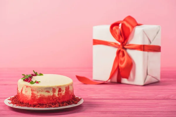 Cake decorated with currants and mint leaves near gift box isolated on pink — Stock Photo