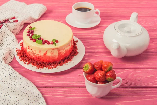 Крупним планом торт, прикрашений смородиною і листя м'яти біля чайного горщика і чашки полуниці — стокове фото