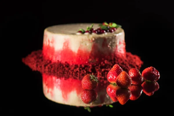 White cake decorated with red currants and mint leaves near strawberries isolated on black — Stock Photo