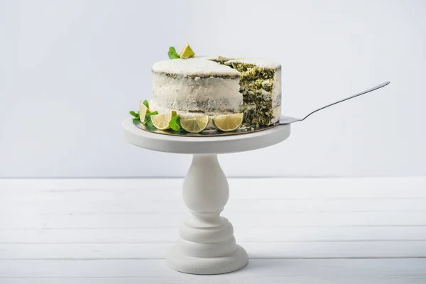 Torta bianca decorata con foglie di menta e fette di linea sul cavalletto isolato su bianco — Foto stock