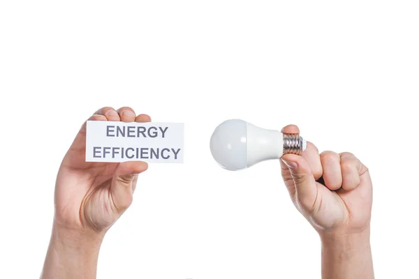 Ausgeschnittene Ansicht männlicher Hände mit Leuchtstofflampe und Papierkarte mit Schriftzug isoliert auf weißem Papier, Energieeffizienzkonzept — Stockfoto