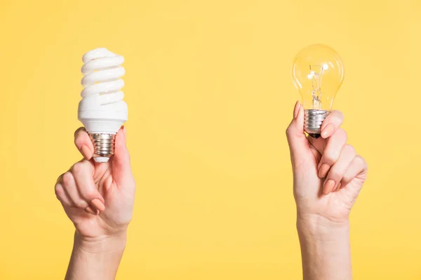 Vista ritagliata della donna che tiene lampade fluorescenti e led in mani isolate su giallo, concetto di efficienza energetica — Foto stock