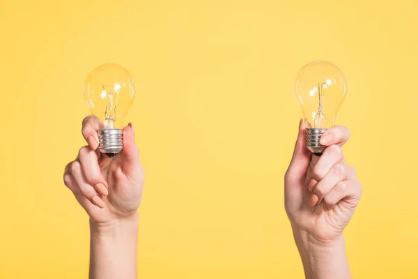 Vista ritagliata della donna che tiene le lampade a led in mani isolate sul giallo, concetto di efficienza energetica — Foto stock