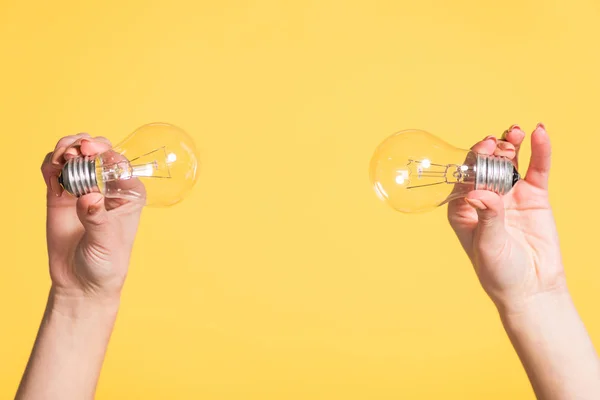 Vista ritagliata delle mani femminili che tengono le lampade a led isolate sul giallo, concetto di efficienza energetica — Foto stock