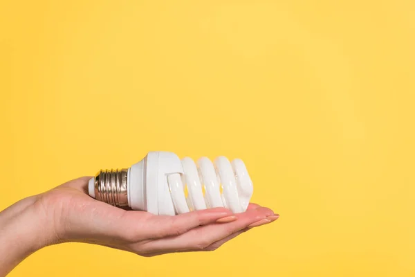 Vista cortada da mulher segurando lâmpada fluorescente isolado em amarelo, conceito de eficiência energética — Fotografia de Stock