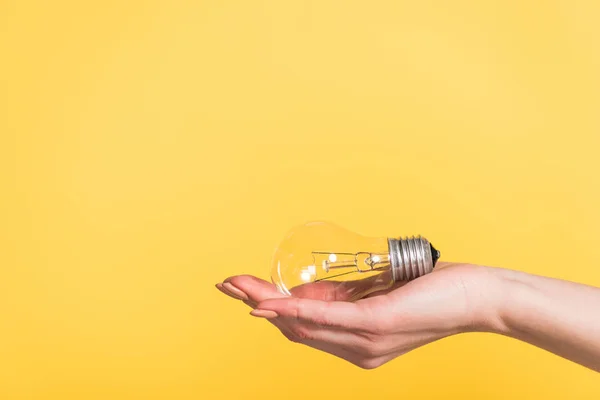 Visão cortada da mulher segurando lâmpada led isolada no amarelo, conceito de eficiência energética — Fotografia de Stock