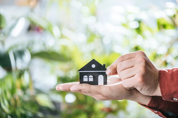 Vista recortada del hombre sosteniendo la casa de papel en las manos, la eficiencia energética en el hogar concepto - foto de stock