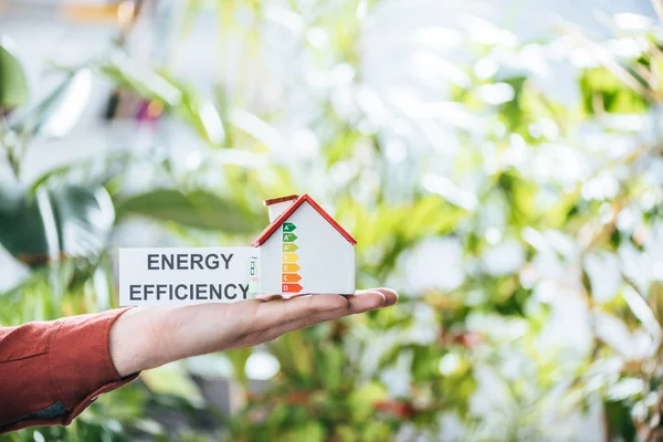 Cropped view of man holding card with lettering and carton house in hands, energy efficiency at home concept — Stock Photo