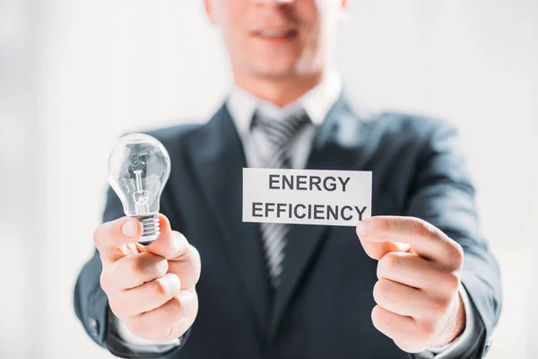 Вибірковий фокус картки і світлодіодні лампи в руках бізнесмена на білому тлі, концепція енергоефективності — стокове фото