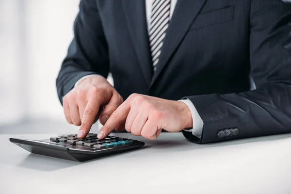 Vista cortada do homem de negócios em terno usando calculadora em fundo branco, conceito de eficiência energética — Fotografia de Stock