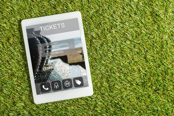 Top view of digital tablet with tickets app on screen on green grass, energy efficiency concept — Stock Photo