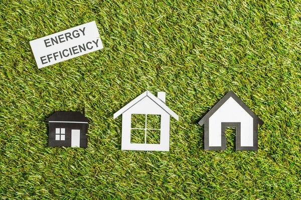 Вид зверху на паперові будинки біля картки з написом, енергоефективність в домашніх умовах концепція — стокове фото