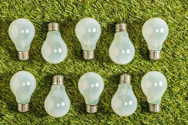 Vista superior de lâmpadas fluorescentes na grama verde, conceito de eficiência energética — Fotografia de Stock