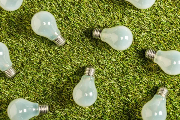 Vista superior de lámparas fluorescentes modernas sobre césped verde, concepto de eficiencia energética - foto de stock