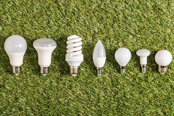 Flat lay of fluorescent lamps on green grass, energy efficiency concept — Stock Photo