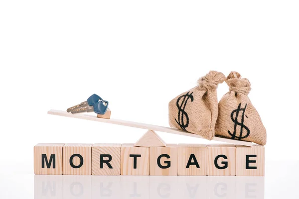 Bloques de madera con letras hipotecarias y escamas con bolsas de dinero y llaves aisladas en blanco - foto de stock