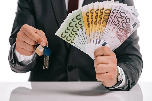 Обрізаний вид бізнесмена, який тримає ключі і євро банкноти ізольовані на білому, іпотечна концепція — стокове фото