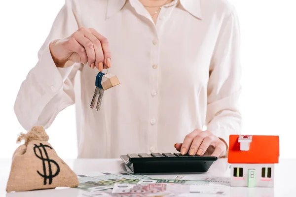 Vista ritagliata di donna d'affari in possesso di chiavi e utilizzando calcolatrice isolato su bianco, concetto di ipoteca — Foto stock