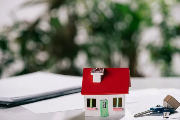 Selektiver Fokus des Hausmodells in der Nähe von Schlüsseln auf weißem Schreibtisch, Hypothekenkonzept — Stockfoto