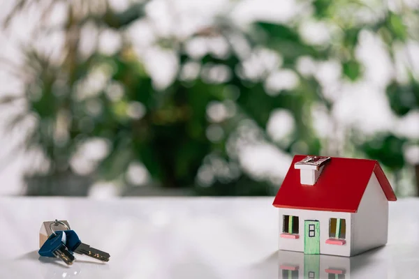 Enfoque selectivo de llaves y modelo de casa en escritorio blanco, concepto de hipoteca - foto de stock