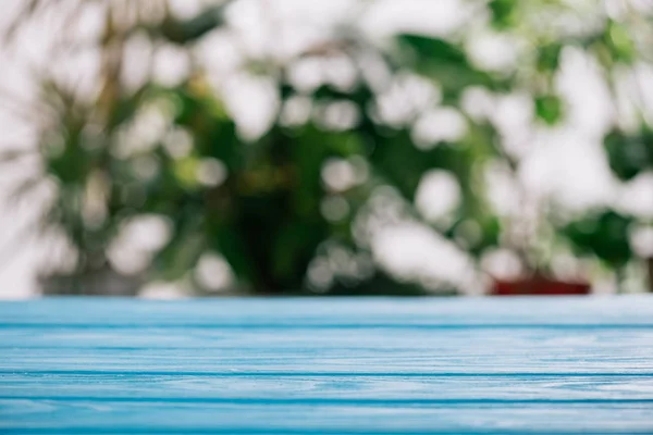 Selektiver Fokus eines blauen Holztisches mit unscharfen Blättern auf dem Hintergrund — Stockfoto