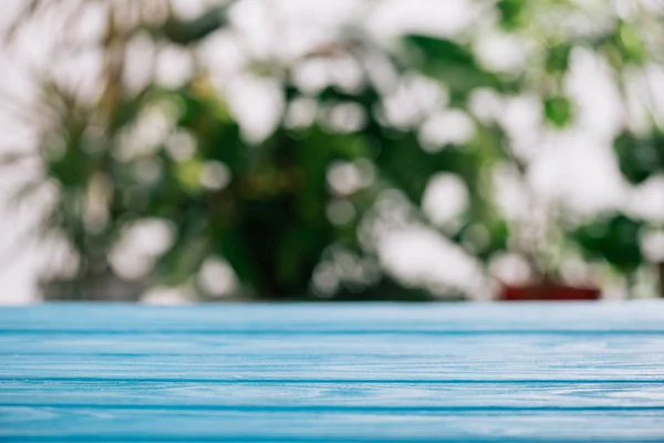 Foyer sélectif de bureau en bois bleu avec des feuilles floues sur le fond — Photo de stock