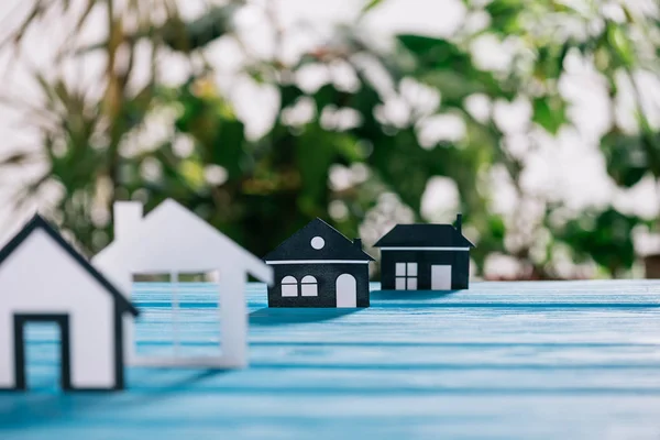 Селективное фокусирование бумажных домов на синем деревянном столе, концепция ипотеки — стоковое фото