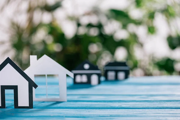 Enfoque selectivo de casas de papel blanco y negro en escritorio de madera azul, concepto de hipoteca - foto de stock