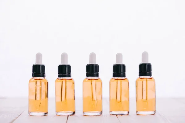 Row of cbd oil in bottles with droppers on wooden surface isolated on white — Stock Photo