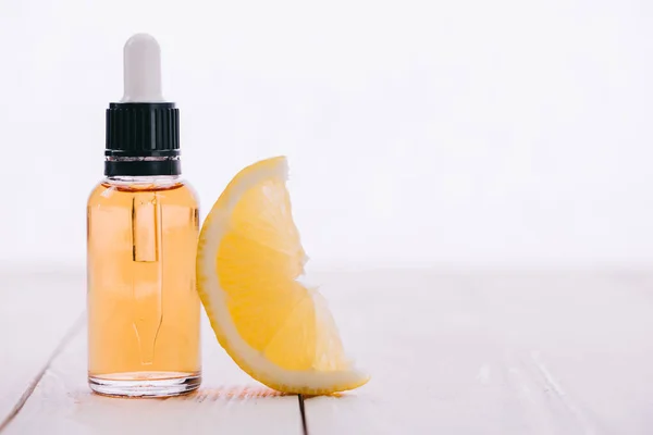 Cbd olio in bottiglia con contagocce e fetta di limone su superficie di legno isolata su bianco — Foto stock