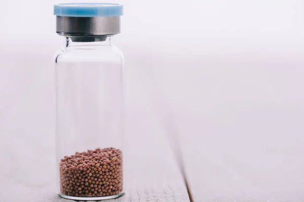 Globules médicaux naturels en bouteille à table en bois sur blanc — Photo de stock