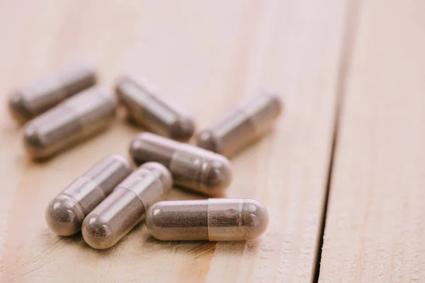 Selective focus of scattered pills on wooden table with copy space — Stock Photo