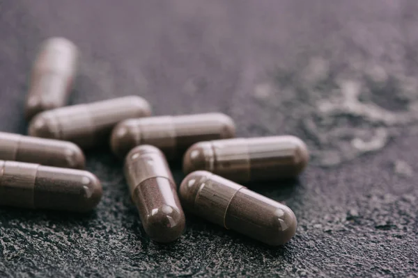 Foco seletivo de pílulas na superfície cinza com espaço de cópia no fundo cinza — Fotografia de Stock