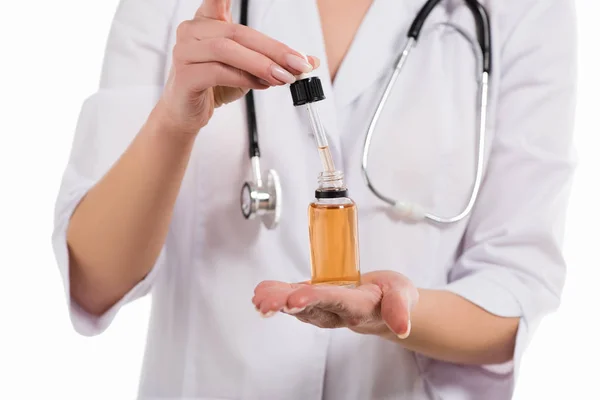 Vue recadrée du médecin femelle ouverture bouteille avec huile et compte-gouttes isolé sur blanc — Photo de stock