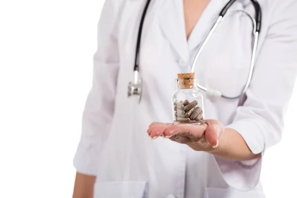 Vista recortada de médico femenino sosteniendo botella con pastillas aisladas en blanco - foto de stock