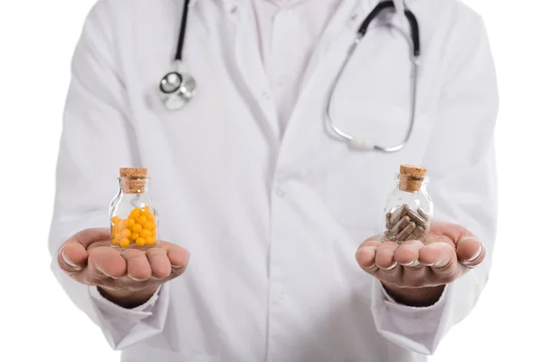 Vue recadrée du médecin masculin tenant deux bouteilles avec des pilules isolées sur blanc — Photo de stock