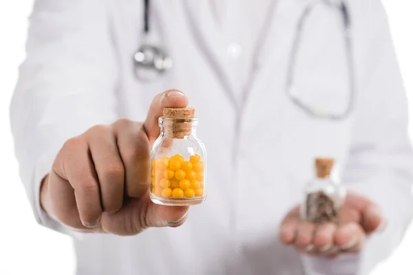Обрізаний вид чоловіка-лікаря, що показує пляшку з таблетками ізольовано на білому — стокове фото