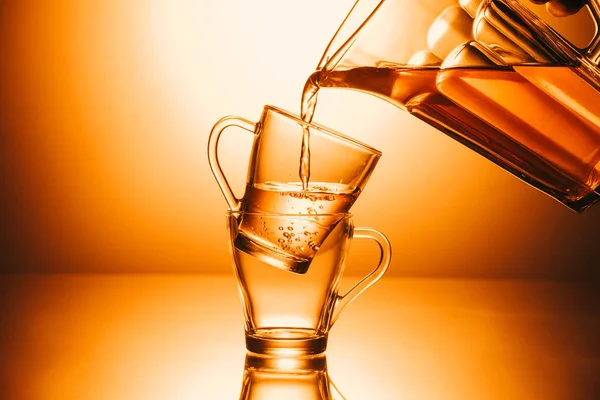 Selective focus of two cups and teapot with stream tea on orange background — Stock Photo